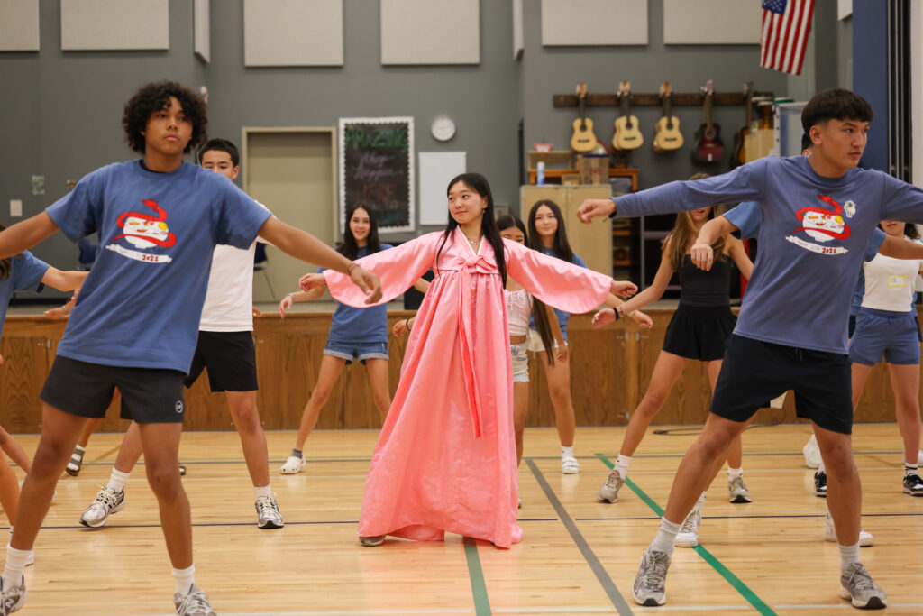 Korean youth, learning cultural dance in a gymnasium.